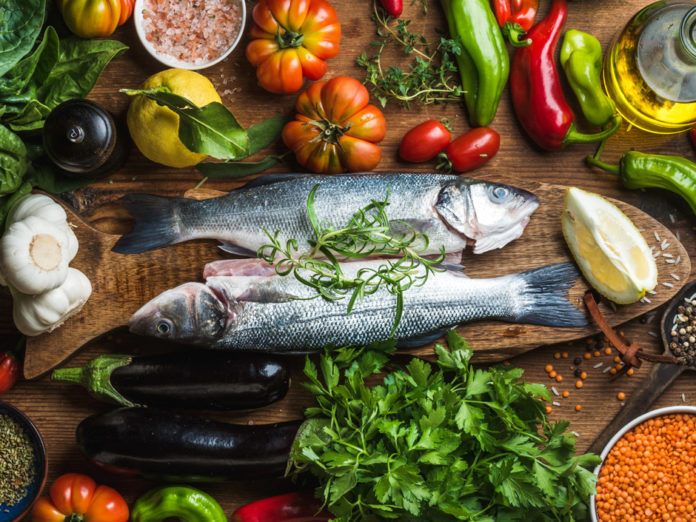 Raw uncooked seabass fish with vegetables, grains, herbs and spices